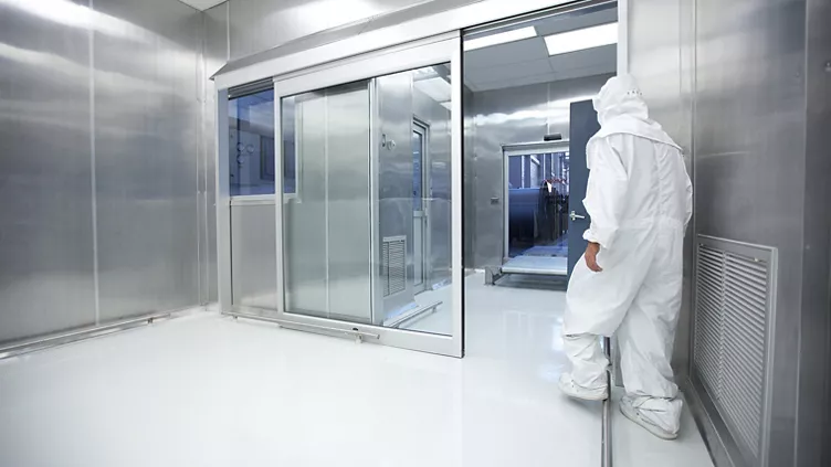 Person in protective suit inside stainless cleanroom